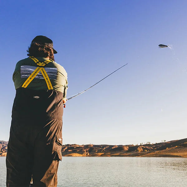 person mid cast with a lure in the air and waterline in the background