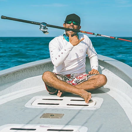 Person sitting on a boat in the middle of the ocean with clear blue water and sky.