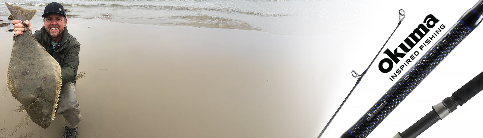Man holding a halibut next to an Okuma fishing rod on a beach.
