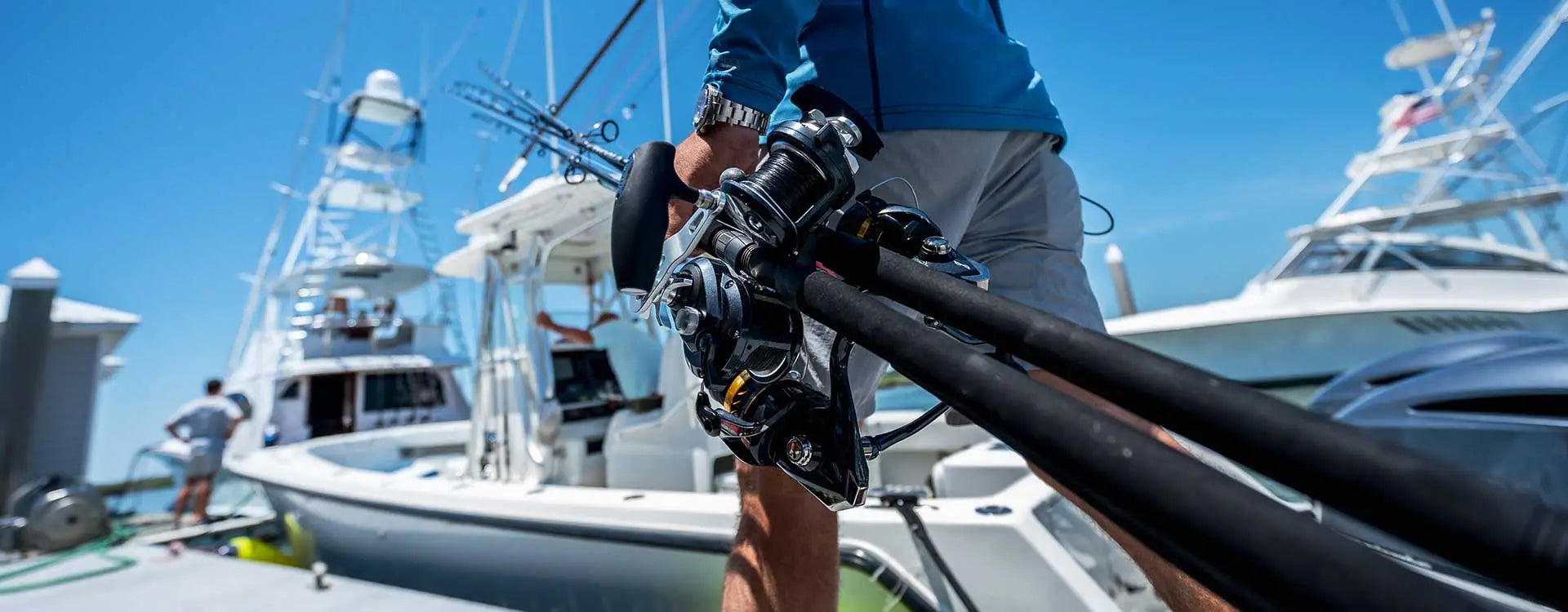 Person holding a large black rod on a boat with other boats in the background