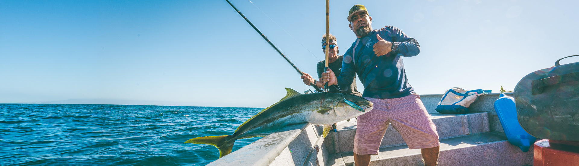 Man on a boat holding a large fish with a clear blue sky and ocean background