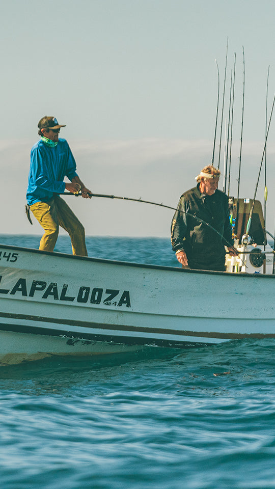 Two men on a boat named 'Lapalooza' in the ocean.