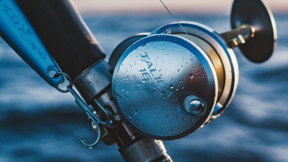 Close-up of a fishing reel with water droplets against a blurred water background