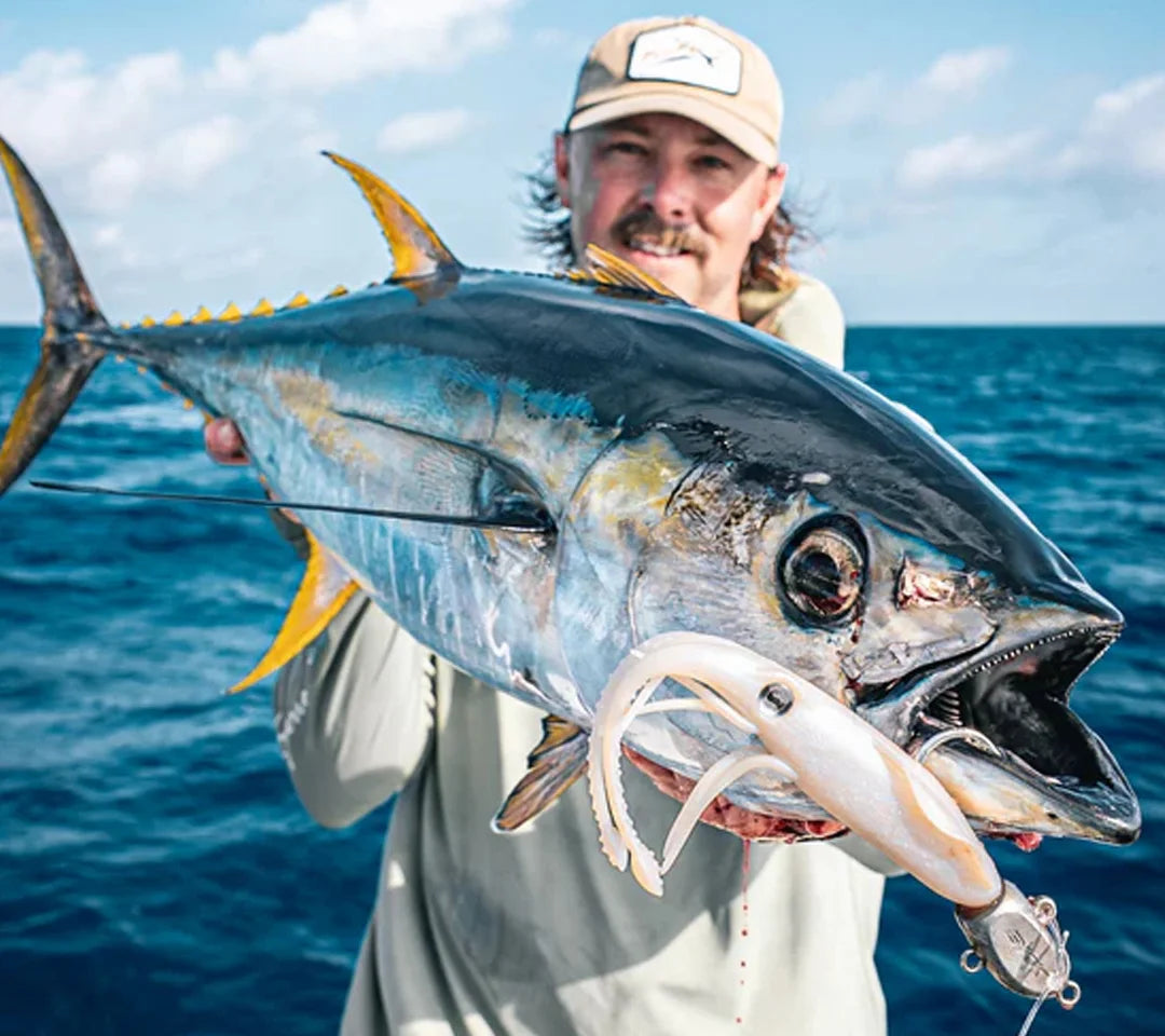 Man holding a tuna with ocean in the background