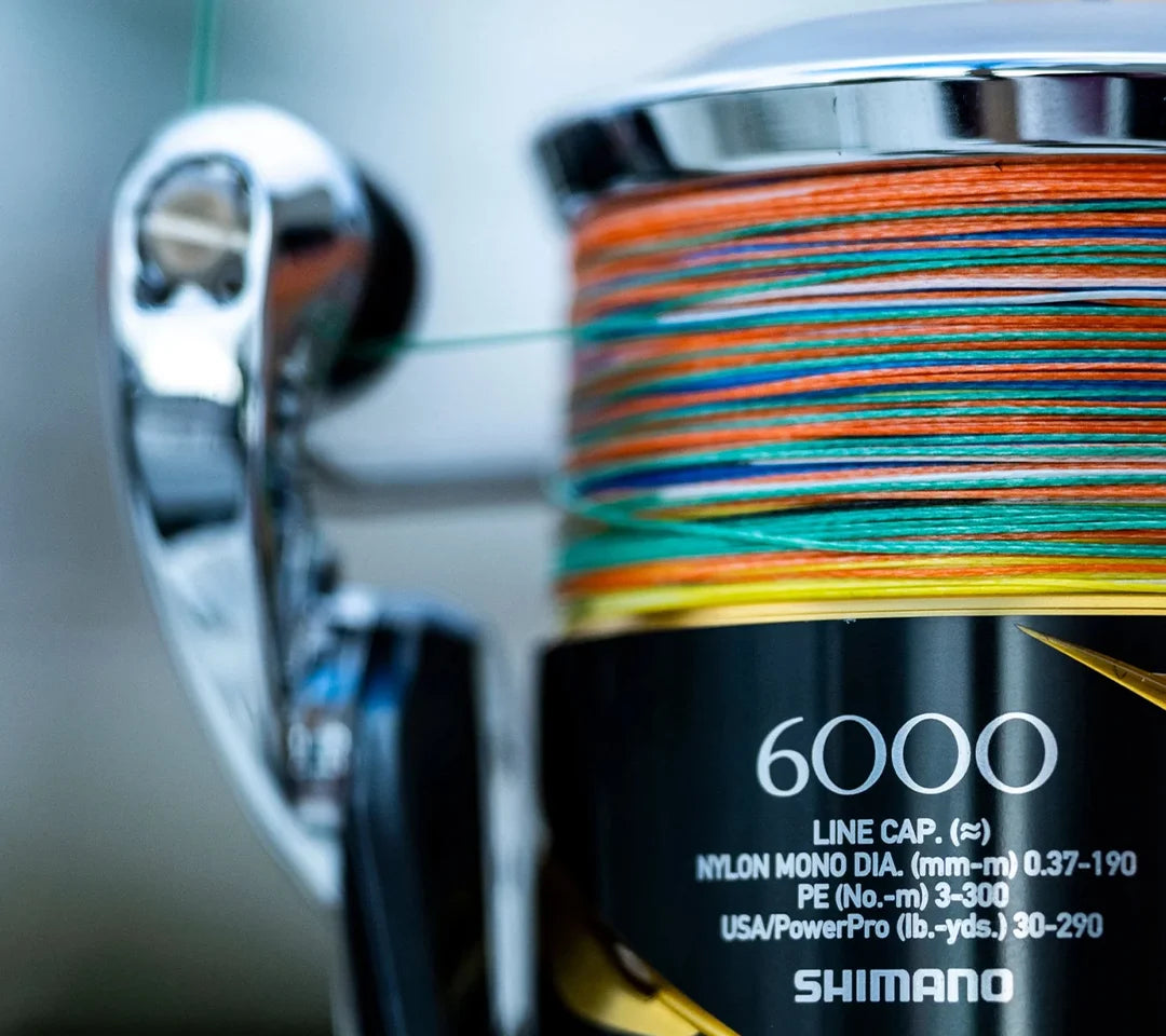 Shimano fishing reel with colorful line spool on a blurred background