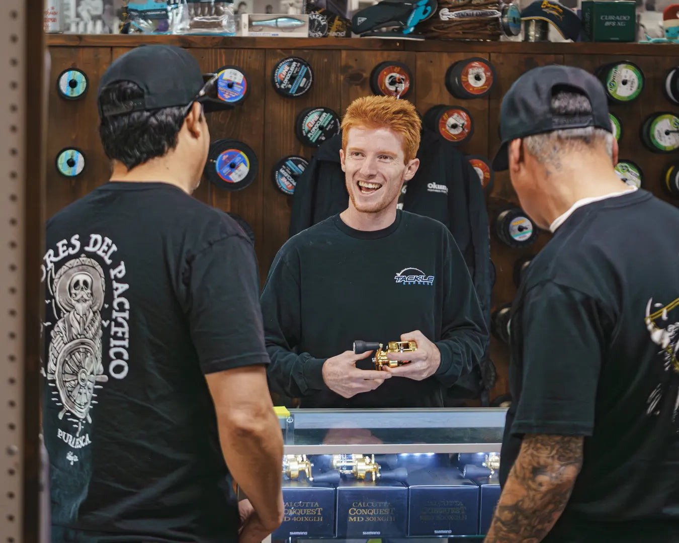 Three men in a store with a focus on a man holding a product, surrounded by shelves with various items.