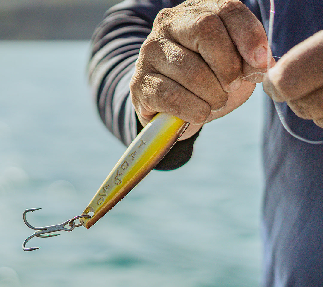 Fishing lure held by a person with a blurred water background